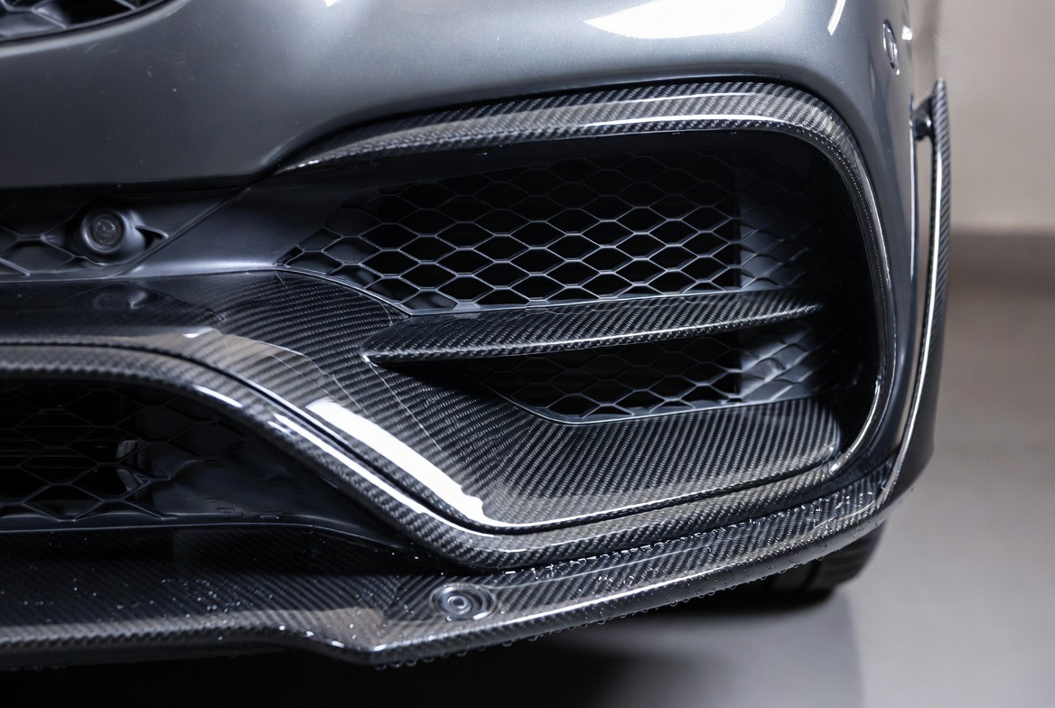 Nærbillede af en carbon Mercedes AMG-kofanger med luftindtag og parkeringssensorer